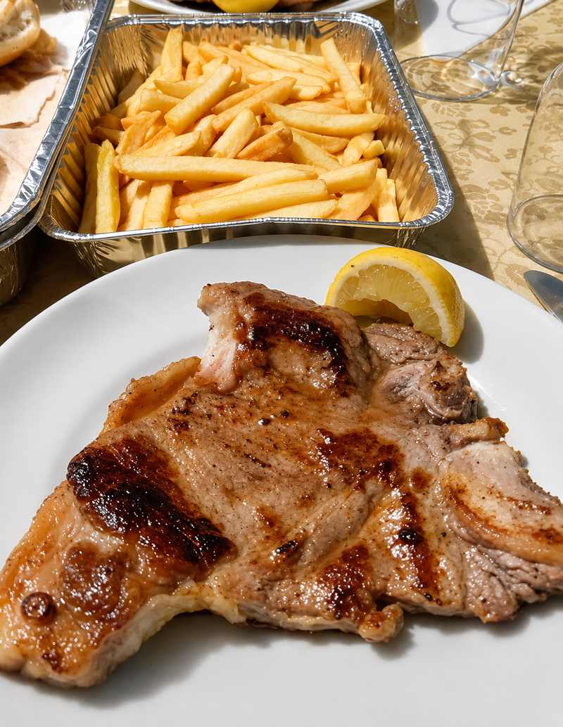 Piatto in giardino con braciola di maiale, limone e patatine